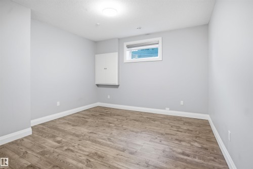 Wood-finish flooring with white trim, light gray walls, and a ceiling-mounted light fixture - 427 Windermere Road Nw, Edmonton, AB - Indoor Photo Showing Other Room