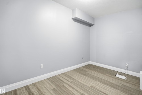Neutral gray wall finishes, wood-finish flooring, white trim, and a built-in soffit - 427 Windermere Road Nw, Edmonton, AB - Indoor Photo Showing Other Room