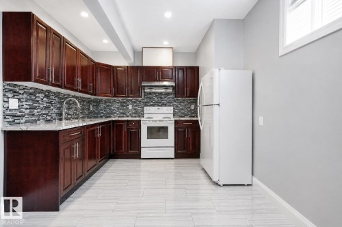 Kitchen featuring dark wood-finish cabinetry, light-toned countertops, tile backsplash, and light-toned tile flooring - 427 Windermere Road Nw, Edmonton, AB - Indoor Photo Showing Kitchen
