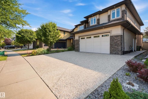 Two-story stucco and stone exterior featuring a two-car garage and a gravel driveway - 427 Windermere Road Nw, Edmonton, AB - Outdoor