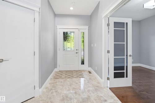 Foyer featuring light-toned tile flooring, recessed lighting, and a white entry door with decorative glass panels - 427 Windermere Road Nw, Edmonton, AB - Indoor Photo Showing Other Room