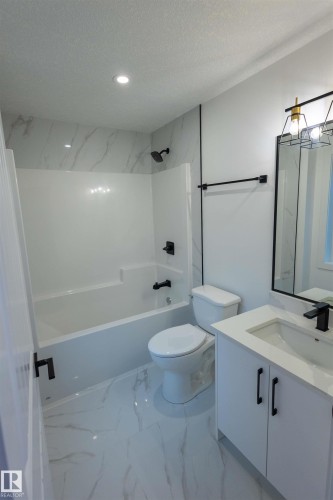 Full bathroom featuring a tub/shower combination with tile surround, white vanity with integrated sink, and white marble-look flooring - 9632 #1 And #2 110 Ave Nw, Edmonton, AB - Indoor Photo Showing Bathroom