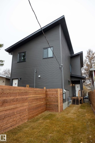Modern exterior featuring dark horizontal siding, an angled roofline, multiple windows, a wood fence, and an exterior staircase - 9632 #1 And #2 110 Ave Nw, Edmonton, AB - Outdoor With Exterior