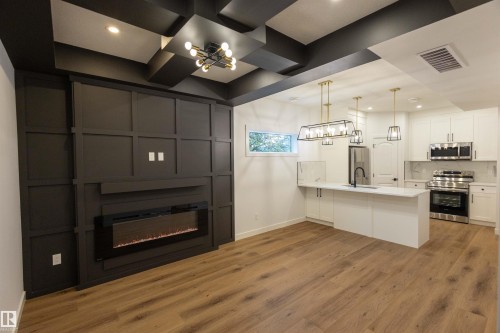 Open-concept living area featuring a built-in electric fireplace, accent wall paneling, and wood-finish flooring - 9632 #1 And #2 110 Ave Nw, Edmonton, AB - Indoor Photo Showing Kitchen With Upgraded Kitchen
