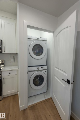 Stackable laundry unit with wood-finish flooring and a white paneled door - 9632 #1 And #2 110 Ave Nw, Edmonton, AB - Indoor Photo Showing Laundry Room
