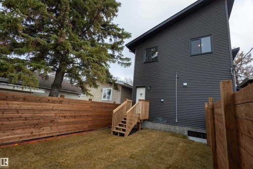 Contemporary exterior with dark horizontal siding, showcasing a wooden deck and staircase leading to a rear entry door - 9632 #1 And #2 110 Ave Nw, Edmonton, AB - Outdoor With Exterior