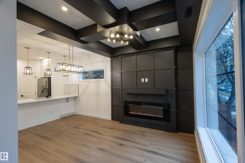 Coffered ceiling, wood-finish flooring, built-in electric fireplace, contemporary light fixtures, and white cabinetry - 9632 #1 And #2 110 Ave Nw, Edmonton, AB - Indoor With Fireplace