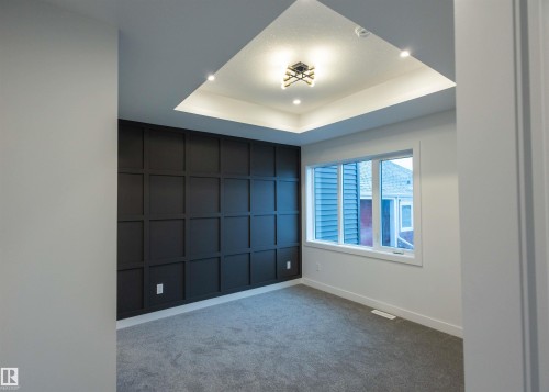 Tray ceiling with recessed lighting and a central fixture, accent wall with applied molding, large window, and gray carpet flooring - 9632 #1 And #2 110 Ave Nw, Edmonton, AB - Indoor Photo Showing Other Room