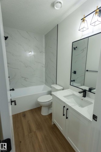 Contemporary bathroom featuring a white vanity with integrated sink, black fixtures, and a tiled tub surround - 9632 #1 And #2 110 Ave Nw, Edmonton, AB - Indoor Photo Showing Bathroom