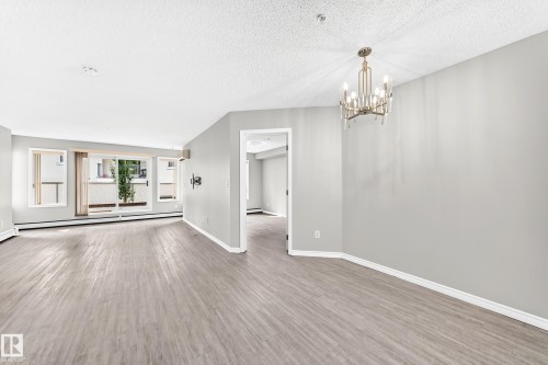 Light wood-finish flooring throughout, bright white walls, and a contemporary chandelier - #137 9704 174 St Nw, Edmonton, AB - Indoor