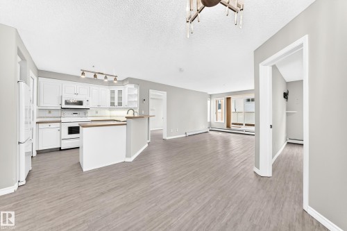 Open-concept living space featuring wood-finish flooring and neutral paint throughout - #137 9704 174 St Nw, Edmonton, AB - Indoor Photo Showing Kitchen