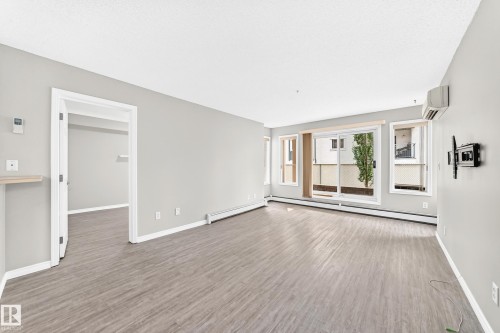 Wood-finish flooring throughout, light gray wall finishes, and a sliding glass door to the exterior - #137 9704 174 St Nw, Edmonton, AB - Indoor Photo Showing Other Room