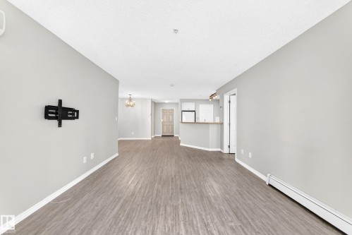 Wood-finish flooring, light gray wall paint, and white trim - #137 9704 174 St Nw, Edmonton, AB - Indoor Photo Showing Other Room
