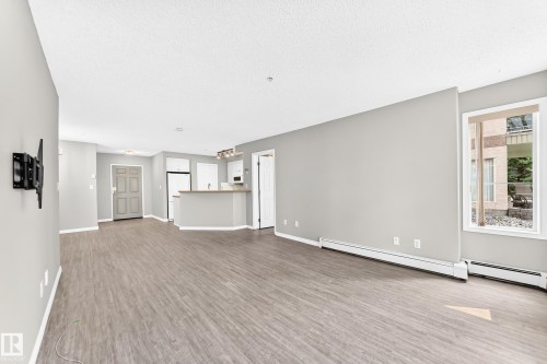 Wood-finish flooring, light grey wall paint, and a window with white trim - #137 9704 174 St Nw, Edmonton, AB - Indoor Photo Showing Other Room