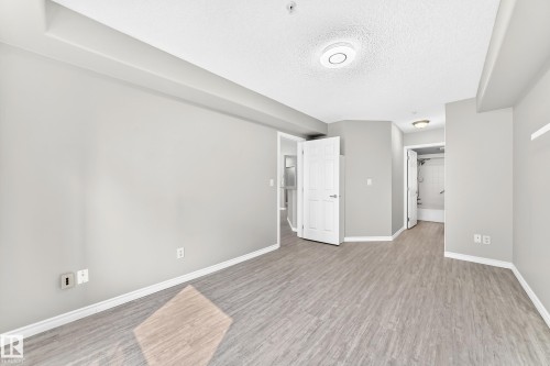 Spacious room with light gray walls, wood-finish flooring, and white trim - #137 9704 174 St Nw, Edmonton, AB - Indoor Photo Showing Other Room
