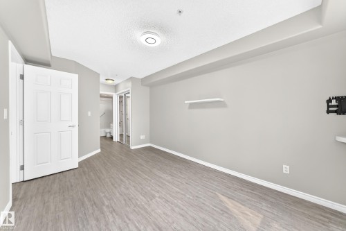Wood-finish flooring, light gray wall paint, and overhead lighting - #137 9704 174 St Nw, Edmonton, AB - Indoor Photo Showing Other Room