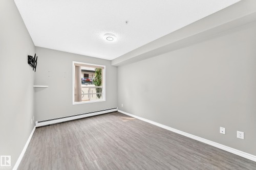 Wood-finish flooring, neutral wall tones, window with white trim, and white baseboards - #137 9704 174 St Nw, Edmonton, AB - Indoor Photo Showing Other Room