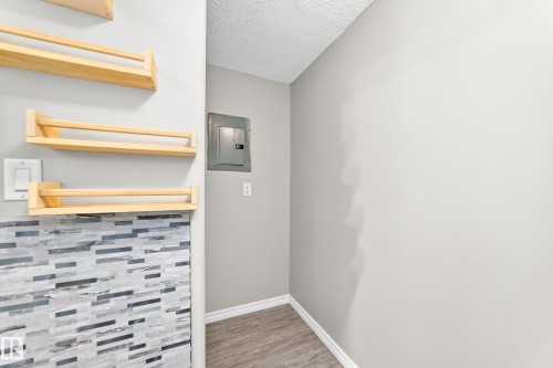 Wood-finish flooring with white trim, electrical panel, and light-toned walls - #137 9704 174 St Nw, Edmonton, AB - Indoor Photo Showing Other Room
