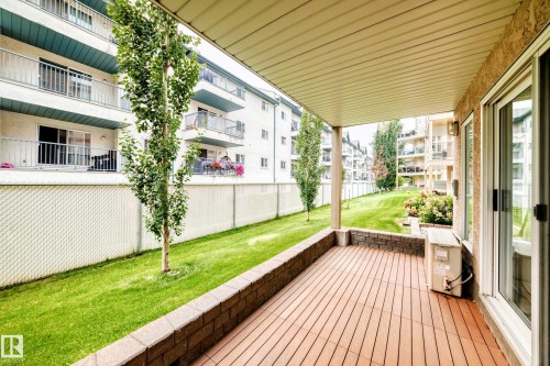 Covered patio featuring wood-finish decking and stone retaining wall - #137 9704 174 St Nw, Edmonton, AB - Outdoor With Exterior