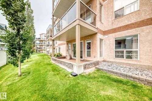 Ground-level patio with stone veneer retaining wall and adjacent rock garden - #137 9704 174 St Nw, Edmonton, AB - Outdoor With Exterior