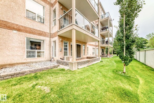 Manicured lawn, elevated patio, multi-level balconies with glass railings, and a privacy fence - #137 9704 174 St Nw, Edmonton, AB - Outdoor