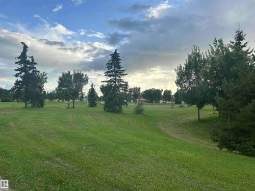 Expansive green space featuring a manicured lawn, mature trees, and a distant gazebo - #137 9704 174 St Nw, Edmonton, AB - Outdoor With View