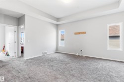 Tray ceiling detail, neutral gray wall tones, plush gray carpeting, white trim, and multiple windows providing natural light - 