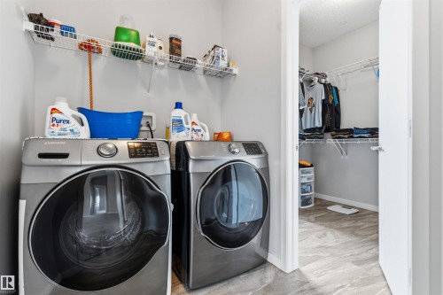 Laundry area featuring a front-load washer and dryer, wire shelving, and light gray wall paint - 1103 26 Avenue Nw, Edmonton, AB - Indoor Photo Showing Laundry Room