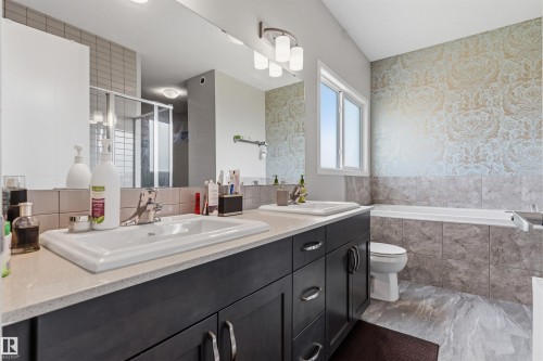 Dual vanity with white undermount sinks, stone-look countertops, and dark wood-finish cabinetry - 1103 26 Avenue Nw, Edmonton, AB - Indoor Photo Showing Bathroom