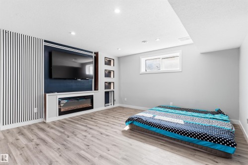 Built-in media console with fireplace, recessed lighting, wood-finish flooring, and white window with blinds - 1103 26 Avenue Nw, Edmonton, AB - Indoor Photo Showing Bedroom