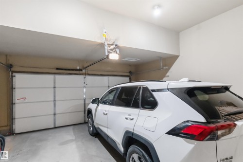 Attached garage with a white sectional door, concrete flooring, and overhead lighting - 1103 26 Avenue Nw, Edmonton, AB - Indoor Photo Showing Garage