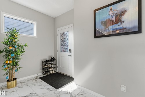 White panel door with decorative glass insert, smart lock hardware, and a high-set horizontal window - 1103 26 Avenue Nw, Edmonton, AB - Indoor Photo Showing Other Room