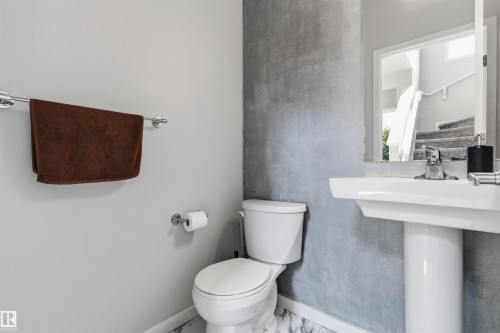 Pedestal sink with chrome fixtures, white toilet, and polished chrome towel bar - 1103 26 Avenue Nw, Edmonton, AB - Indoor Photo Showing Bathroom