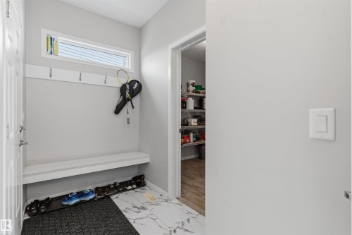 Built-in mudroom bench with coat hooks, transom window, and adjacent pantry with shelving - 1103 26 Avenue Nw, Edmonton, AB - Indoor Photo Showing Other Room