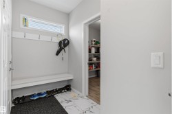 Built-in mudroom bench with coat hooks, transom window, and adjacent pantry with shelving - 