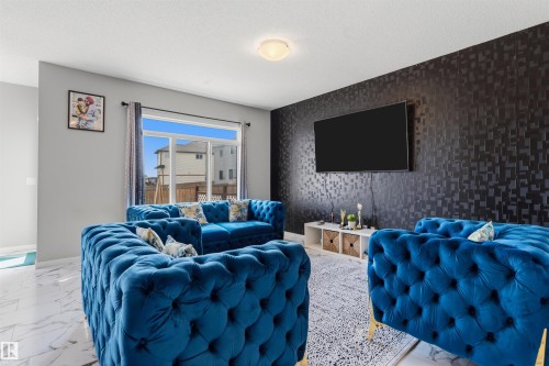 Living area featuring a textured accent wall, light-colored walls, and a glass sliding door - 1103 26 Avenue Nw, Edmonton, AB - Indoor
