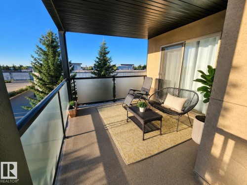 Private balcony featuring a textured floor and frosted glass railing - #301 13907 136 St Nw, Edmonton, AB - Outdoor With Balcony With Deck Patio Veranda With Exterior