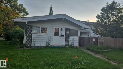 White siding exterior with a white entry door, lattice detail, and a wood fence - 25 Balmoral Drive, St. Albert, AB 