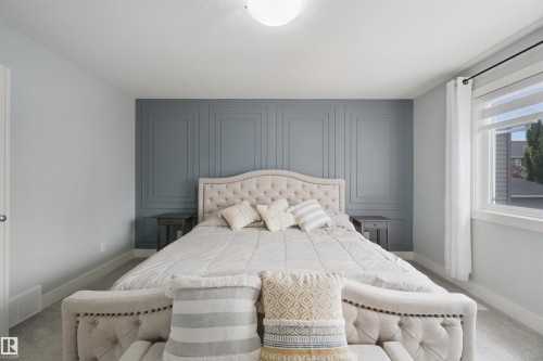 Accent wall with decorative paneling, carpeted flooring, and a large window with roller shades - 7603 Summerside Grande Boulevard Sw, Edmonton, AB - Indoor Photo Showing Bedroom
