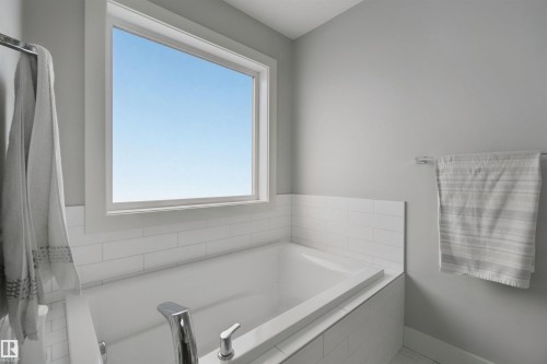 Built-in soaking tub with chrome fixtures, subway tile surround, and a large window - 7603 Summerside Grande Boulevard Sw, Edmonton, AB - Indoor Photo Showing Bathroom