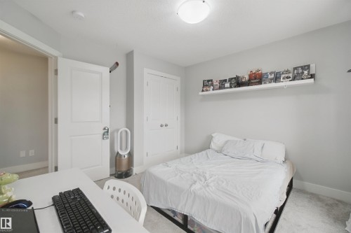 White interior doors, wall-mounted shelving, overhead flush mount lighting, and neutral wall paint - 7603 Summerside Grande Boulevard Sw, Edmonton, AB - Indoor Photo Showing Bedroom