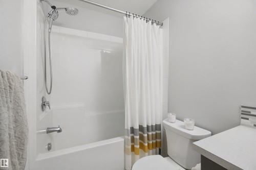 Bathtub with shower fixture, chrome hardware, and white tile surround - 7603 Summerside Grande Boulevard Sw, Edmonton, AB - Indoor Photo Showing Bathroom