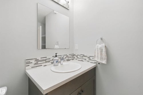 Vanity featuring a white countertop, undermount sink, and mosaic tile backsplash - 7603 Summerside Grande Boulevard Sw, Edmonton, AB - Indoor Photo Showing Bathroom