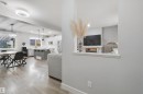 Open-concept living space with wood-finish flooring, a contemporary ceiling light fixture, a kitchen island with pendant lighting, and a built-in electric fireplace - 7603 Summerside Grande Boulevard Sw, Edmonton, AB  - Indoor 