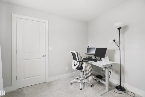 Plush carpeting, light gray wall finishes, white trim, and a white two-panel door with a brushed nickel knob - 7603 Summerside Grande Boulevard Sw, Edmonton, AB - Indoor Photo Showing Office