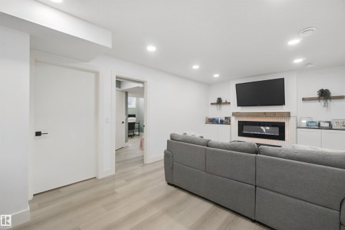 Recessed lighting, wood-finish flooring, built-in electric fireplace with tile surround, wood mantel, and integrated shelving - 7603 Summerside Grande Boulevard Sw, Edmonton, AB - Indoor With Fireplace