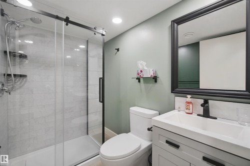Walk-in shower with clear glass door, white rectangular vanity sink, matte black fixtures, framed mirror, and recessed lighting - 7603 Summerside Grande Boulevard Sw, Edmonton, AB - Indoor Photo Showing Bathroom