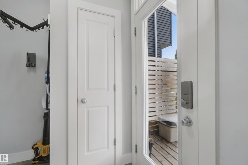 White paneled door, glass-paneled door, brushed nickel door hardware, light wood slatted privacy fence, wood-finish decking - 7603 Summerside Grande Boulevard Sw, Edmonton, AB - Indoor