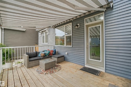 Wood-finish deck with a striped retractable awning, white railing, and exterior siding - 7603 Summerside Grande Boulevard Sw, Edmonton, AB - Outdoor With Deck Patio Veranda With Exterior
