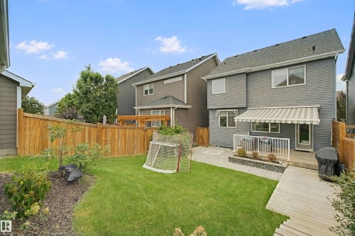 Expansive backyard featuring a manicured lawn, wood fencing, a raised deck, and an awning-covered patio area - 7603 Summerside Grande Boulevard Sw, Edmonton, AB - Outdoor With Deck Patio Veranda With Exterior